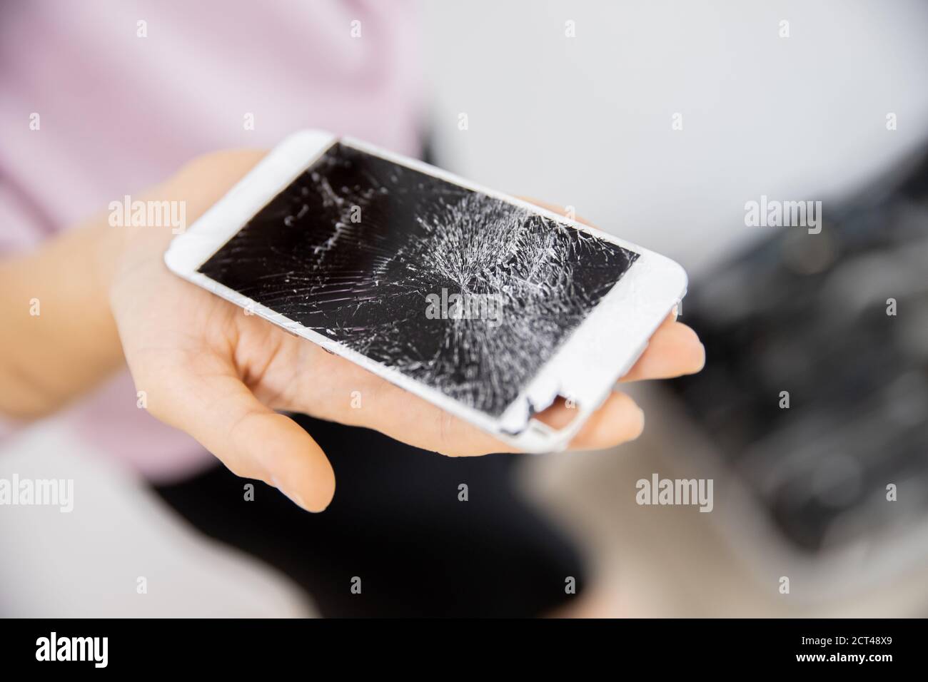 Écran de verre cassé du téléphone dans les mains de la femme, fond blanc Banque D'Images