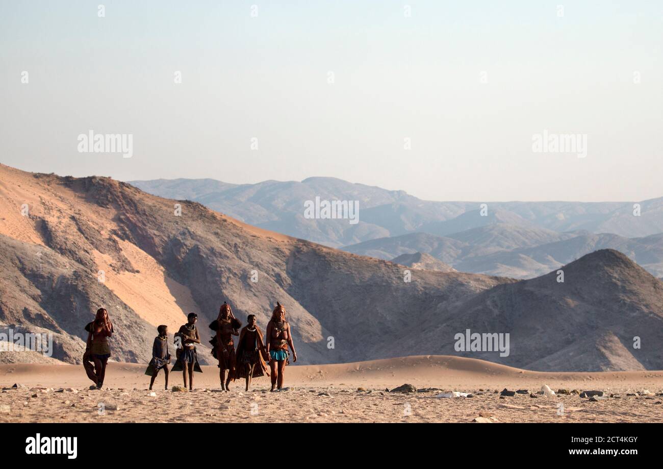 Une promenade familiale Himba à travers des terres arides dans la région de Kunene, dans le nord de la Namibie. Banque D'Images