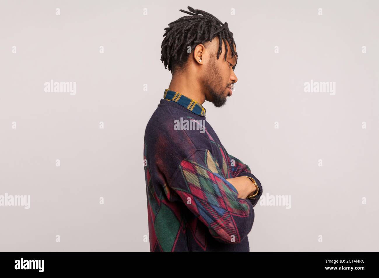 Vue latérale d'un Africain déprimé contrarié avec des dreadlocks debout seul, croisant les bras sur la poitrine, casser, conflit familial. Prise de vue en studio en intérieur Isola Banque D'Images