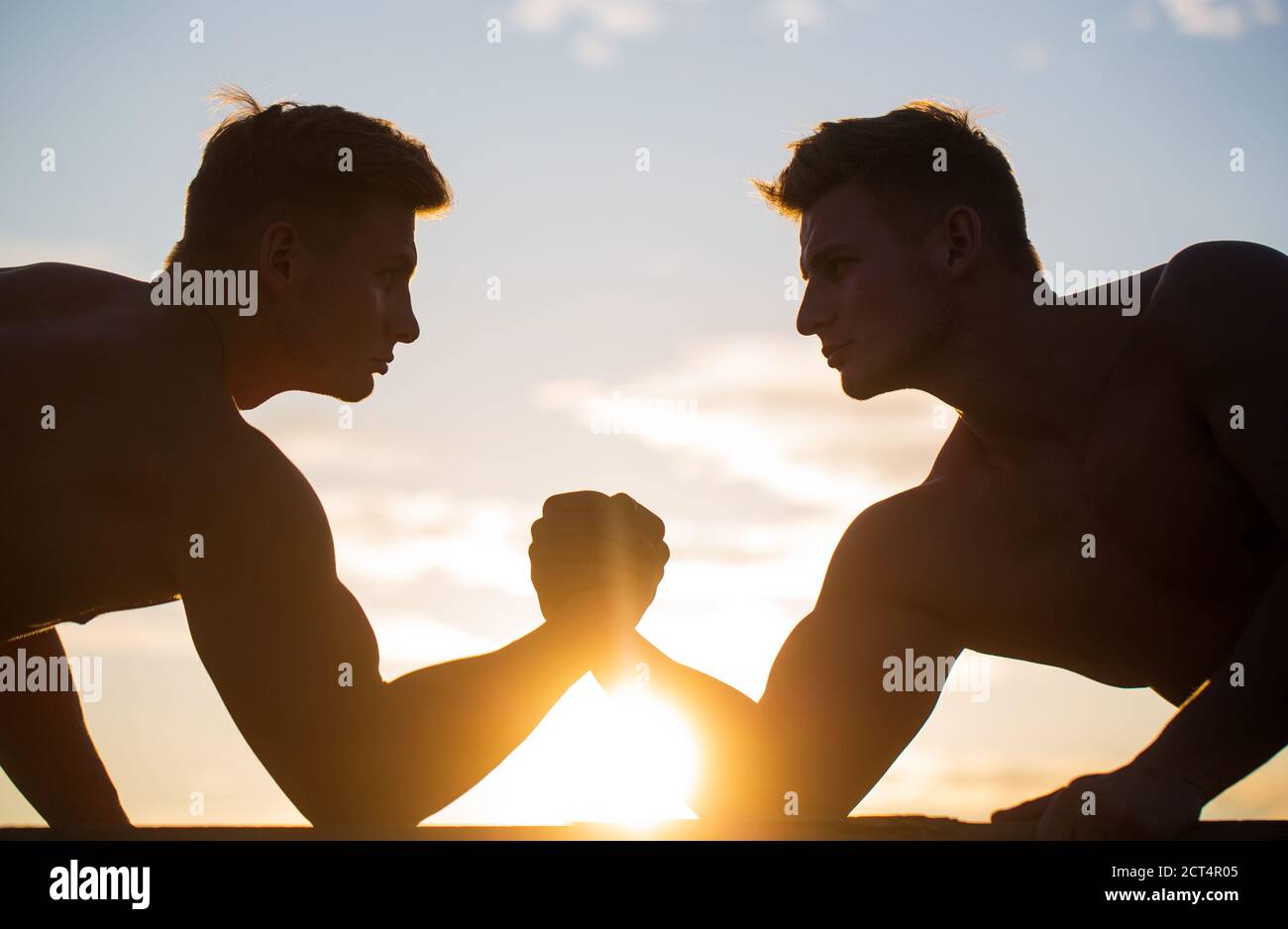 Rivalité, vs, défi, lutte de main. Coucher de soleil, lever du soleil. Hommes mesurant les forces, les bras. Deux hommes luttant. Silhouette de mains qui rivalisent Banque D'Images