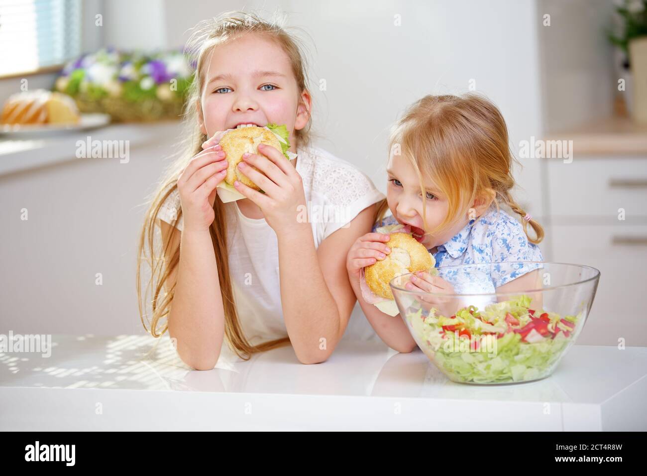Deux enfants mangent des sandwiches pour le petit-déjeuner dans la cuisine Banque D'Images