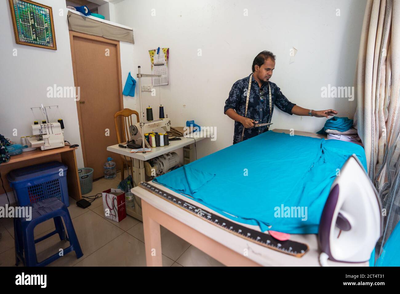 Homme / Maldives - 10 août 2019: Bangladais travailleur immigré homme travaillant dans un petit magasin de vêtements utilisant la machine à repasser sur tissu bleu Banque D'Images