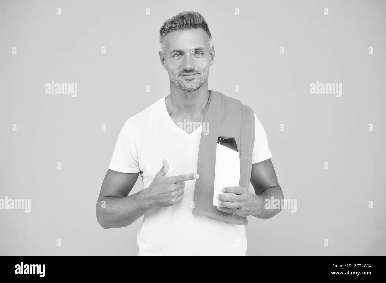 beau homme avec shampooing. guy présentant une bouteille de gel. beauté et santé masculine. routine quotidienne du matin. homme non rasé a des cheveux stylés ou des coupes de cheveux. prêt à prendre une douche avec une serviette. Banque D'Images