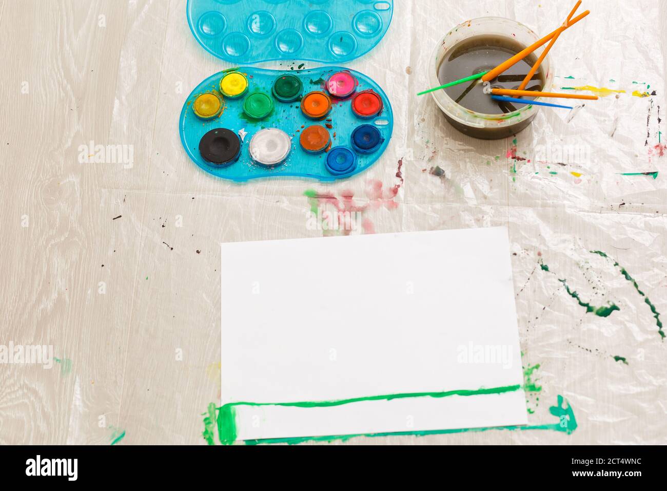 l'enfant dessine avec un pinceau avec aquarelles sur une feuille blanche, un tableau, un lieu de copie Banque D'Images