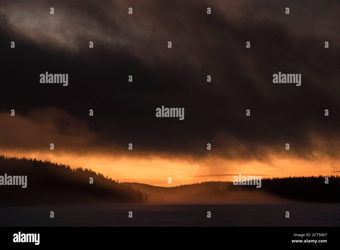Nuages orageux spectaculaires au coucher du soleil sur une forêt et un lac gelé en Laponie, à l'intérieur du cercle arctique de la teh en hiver, arrière-plan avec espace de copie Banque D'Images