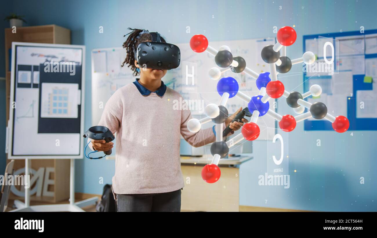 Mignon Girl porte un casque de réalité augmentée et utilise des contrôleurs interagit avec 3D Molecule. Cours de science futuriste pour les enfants en apprentissage Banque D'Images