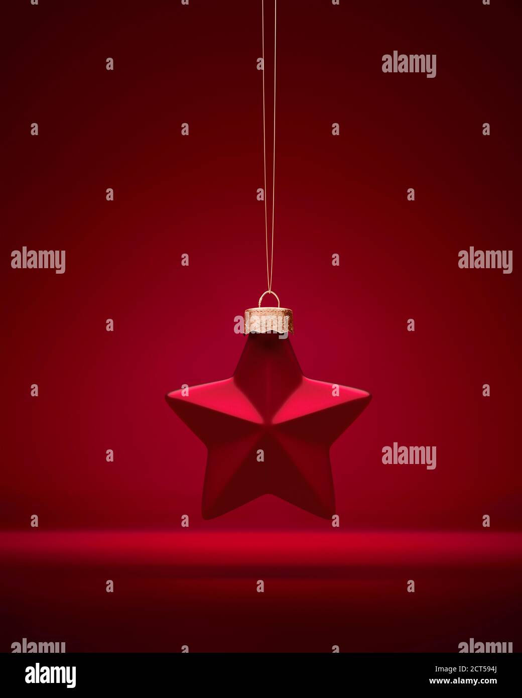 Décoration de Noël rouge à cinq étoiles. Boule en forme suspendue sur une ficelle dorée. Décoration de Noël, concept d'atmosphère festive. Banque D'Images