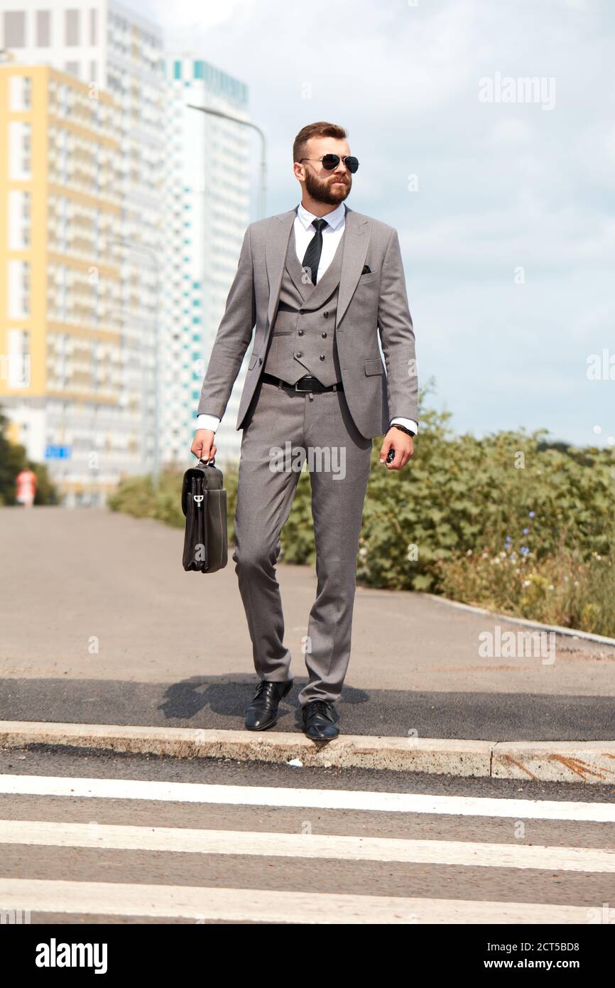 homme d'affaires caucasien se rendant au bureau avec sa sacoche de bureau,  un homme élégant vêque se promette dans la rue pour se rendre au bureau,  traverse les rues de la ville