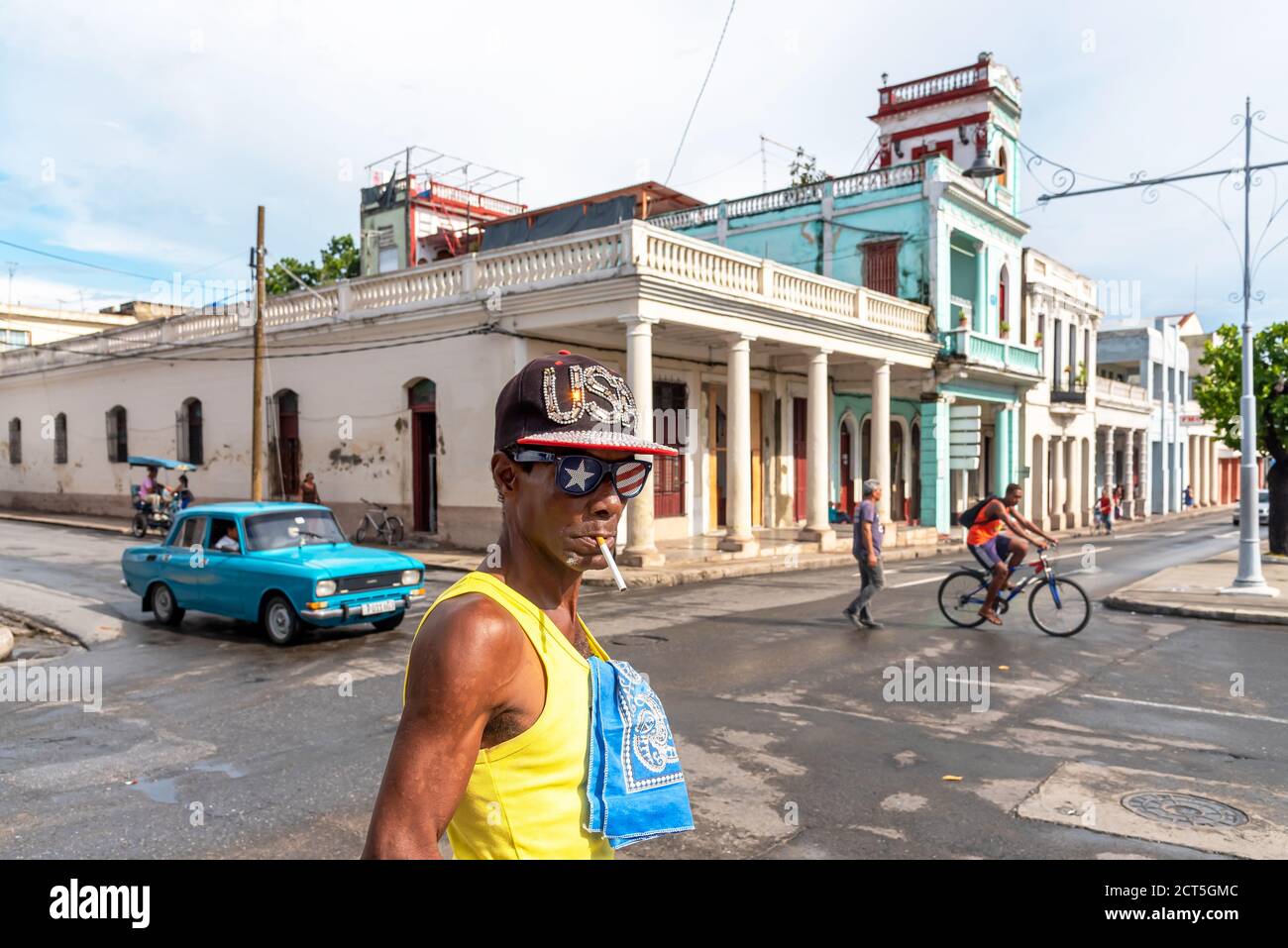 28 août 2019: Homme fumant avec chapeau de drapeau américain et des lunettes dans les rues de Cienfuegos. Cienfuegos, Cuba Banque D'Images