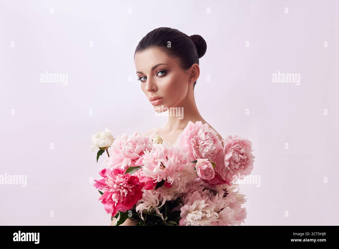 Belle femme aux fleurs de pivoine rose, beauté naturelle, soins de la peau.  Des traits du visage parfaits. Fille posant sur un fond clair Photo Stock -  Alamy