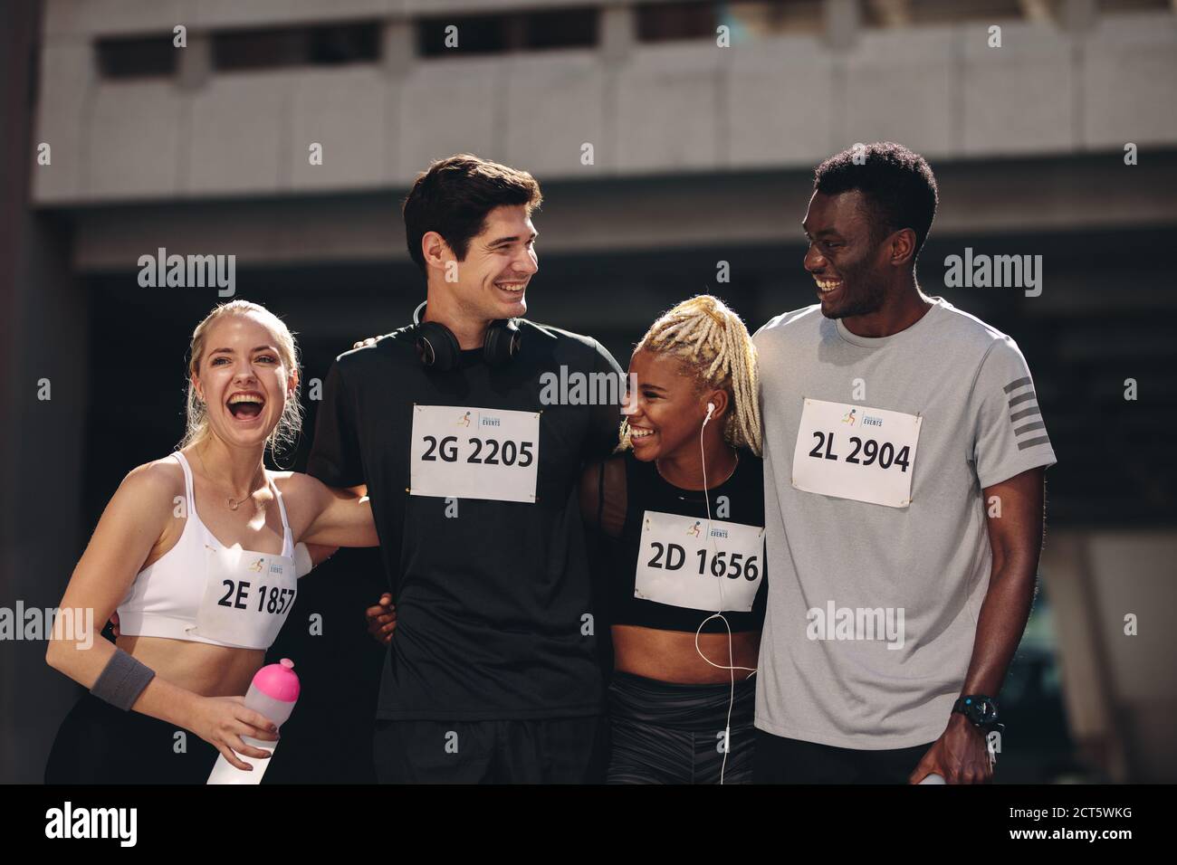 Groupe multiethnique de personnes athlétiques debout ensemble après la course de marathon. Les coureurs internationaux de marathon souriant ensemble après la course. Banque D'Images