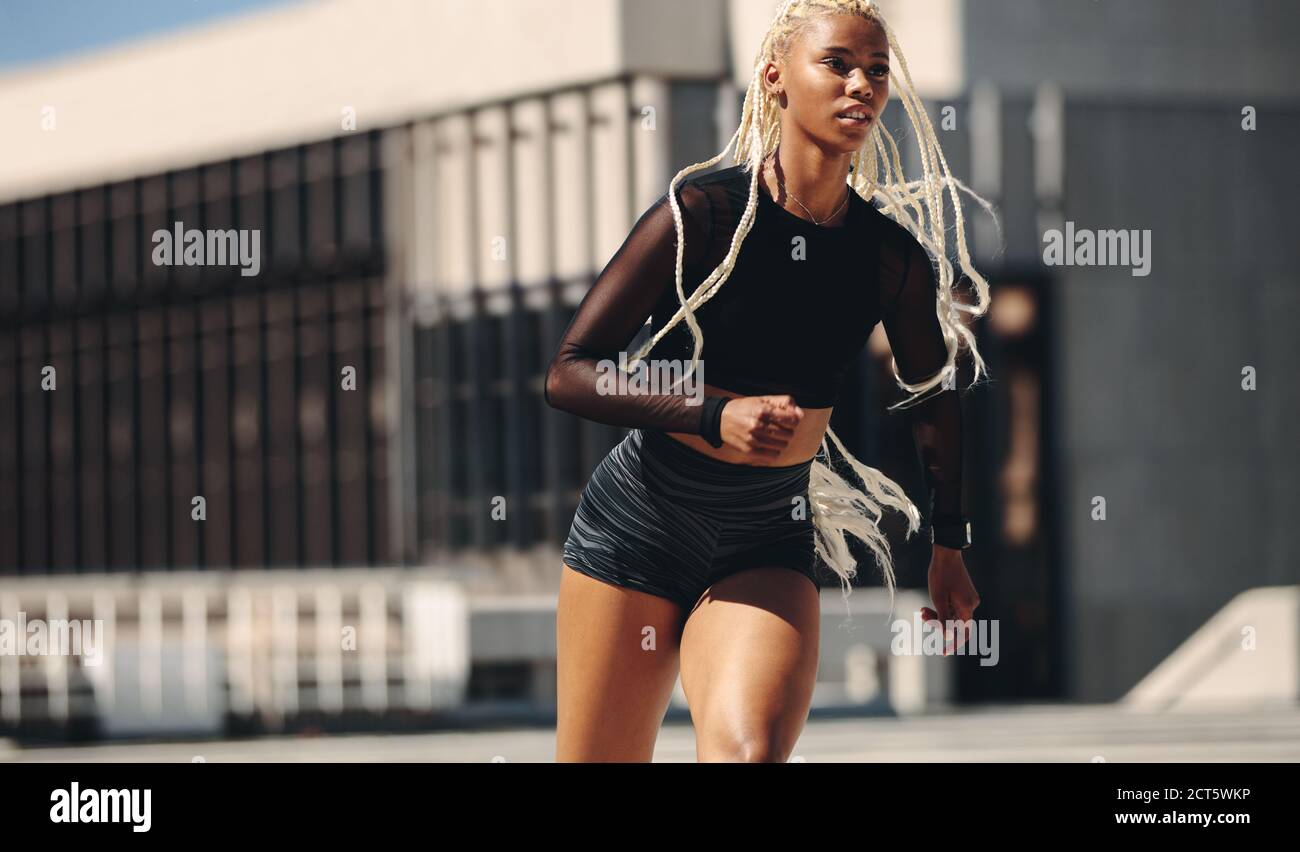 Femme sportive en ville. Femme dans des vêtements de sport le matin courir à l'extérieur. Banque D'Images