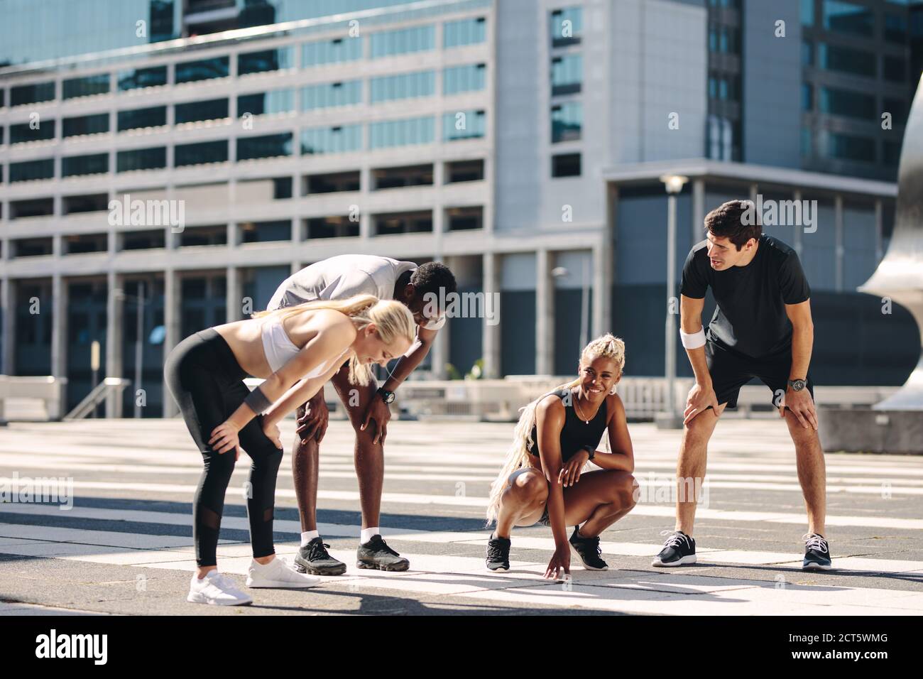 Coureurs de rue multi-ethniques prenant une pause après un entraînement en extérieur. groupe de fitness se reposant et souriant après l'exercice de course dans la ville Banque D'Images