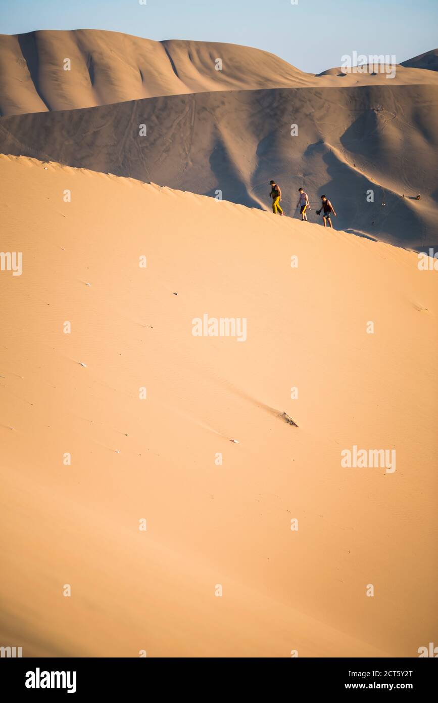 Des personnes grimpant des dunes de sable pour observer le coucher de soleil sur le désert à Huacachina, région de l'ICA, Pérou, Amérique du Sud Banque D'Images