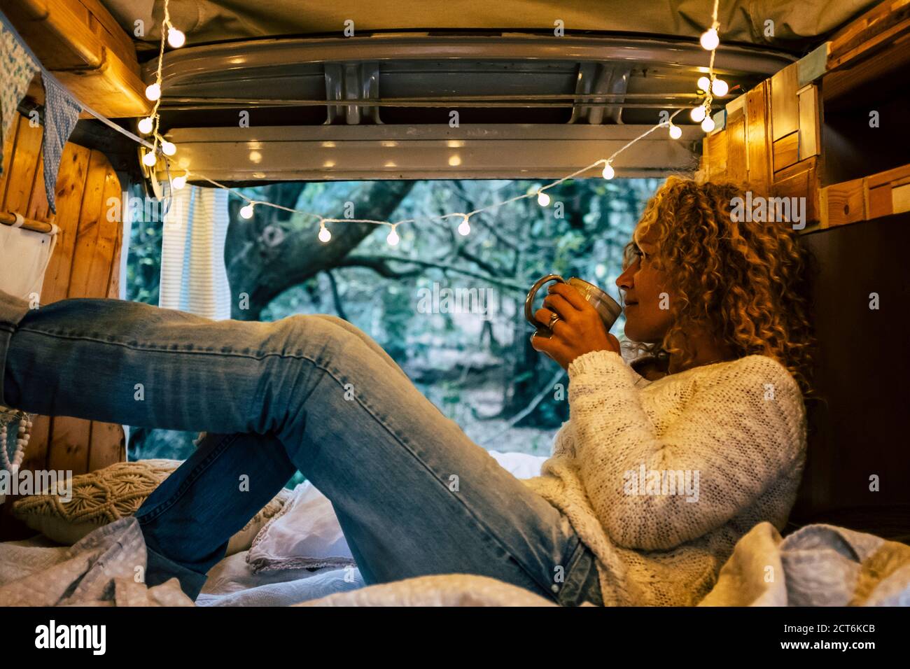 Femme adulte détendue dans une fourgonnette en bois vintage appréciez natoure extérieur et le style de vie de voyage - touristique et véhicule camping avec vue sur la forêt Banque D'Images