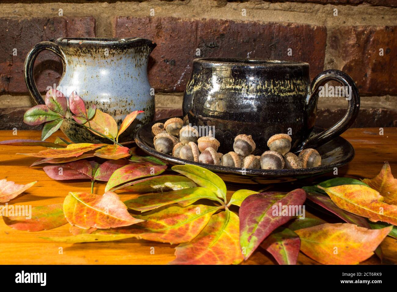 Un thème d'automne encore en vie avec un thé et un beker de lait, entouré de feuilles colorées et de minuscules acorns Banque D'Images