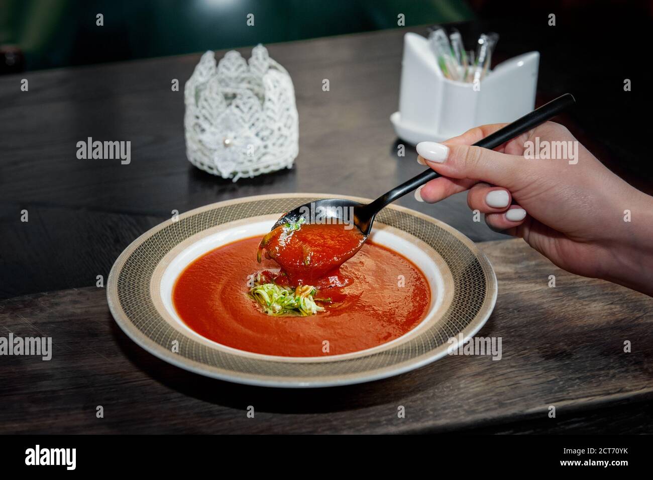 Gaspacho Diet soupe de tomates avec des herbes et concombre sur une assiette. Une main de femme avec une cuillère de soupe. Gros plan Banque D'Images