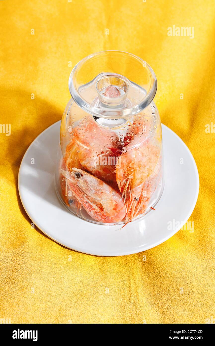 Crevettes surgelées en verre sur fond jaune.cuisine conceptuelle Banque D'Images