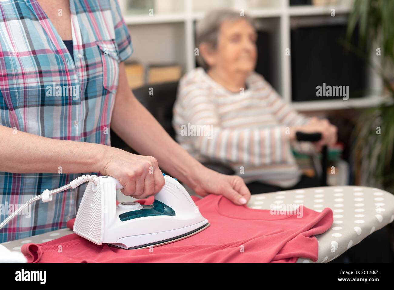 Aide à la maison pour le repassage de vêtements pour femme âgée Photo Stock  - Alamy