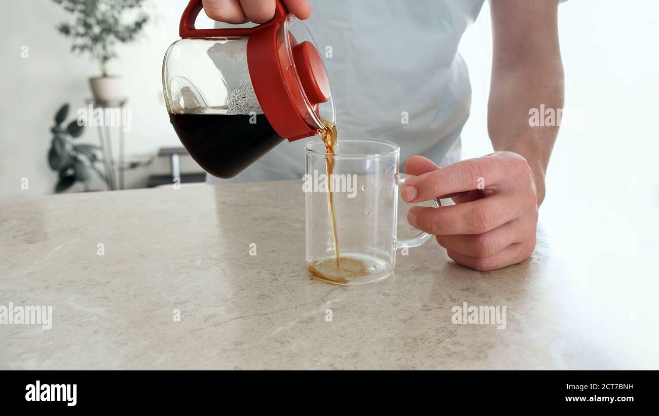 L'homme verse un café fraîchement infusé dans une tasse de verre à