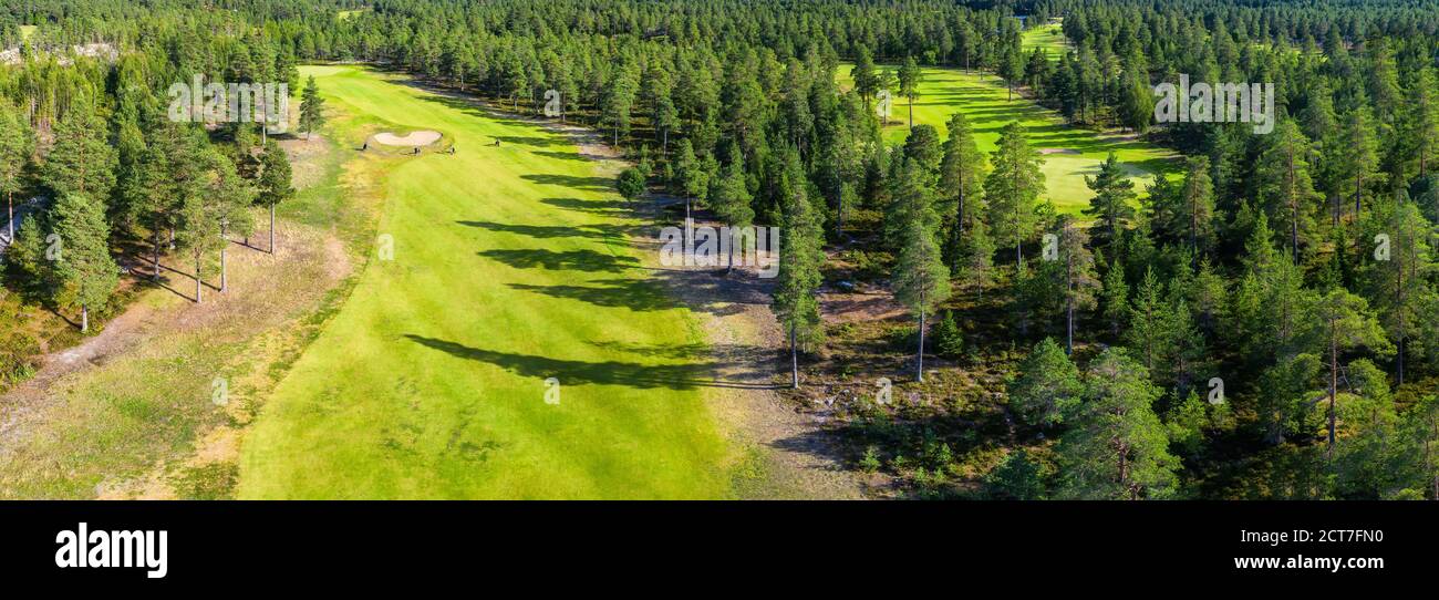 Panorama aérien sur quelques longs parcours de golf étroits dans la forêt du Nord. Des personnes non identifiées jouent au golf sur le parcours de golf, des pins autour, Northern Scandina Banque D'Images