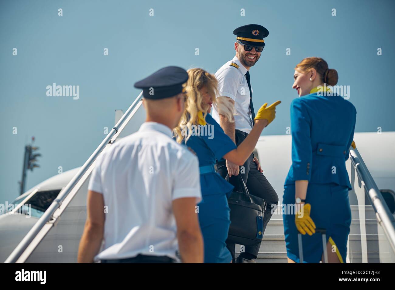 De magnifiques agents de bord avec des collègues près de la rampe d'accès mobile de l'aéroport Banque D'Images