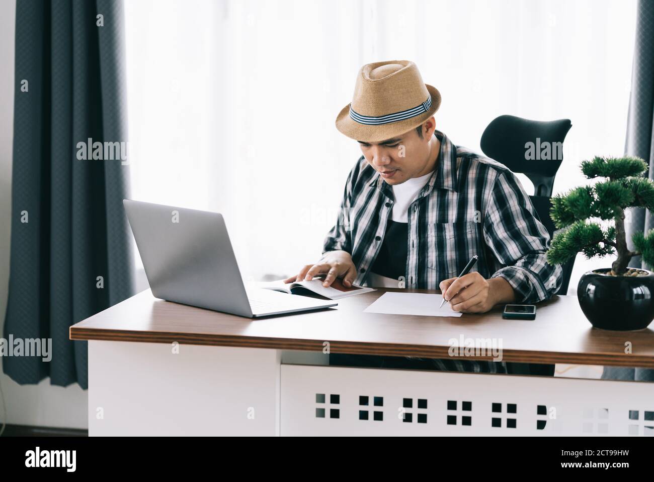 Un jeune homme asiatique assis à sa table pour lire et prendre des notes et planifier le travail au bureau à domicile. Rester à la maison. Quarantaine, concept d'objectif de vie Banque D'Images