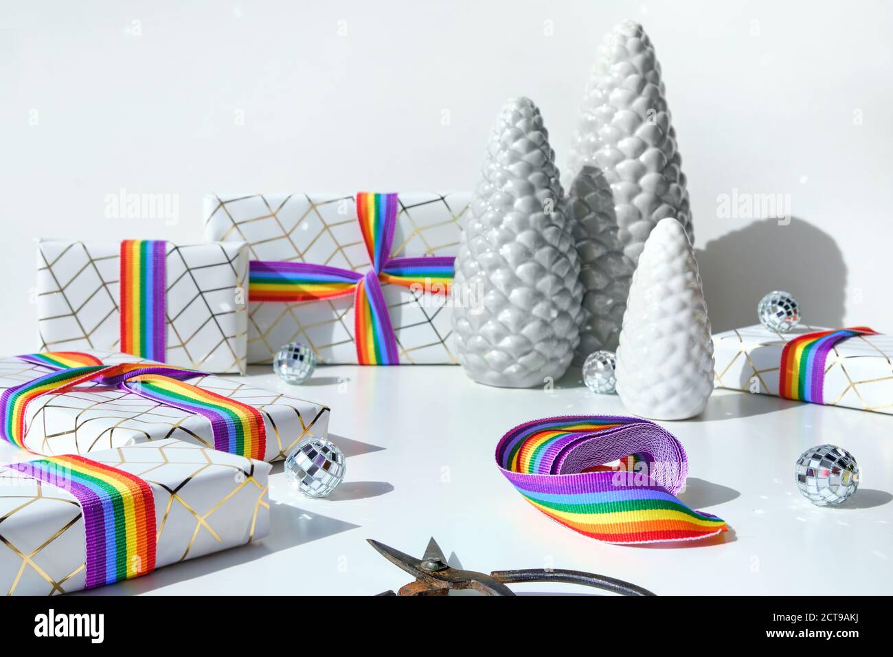 Cadeaux de Noël avec ruban arc-en-ciel aux couleurs du drapeau de la communauté LGBT. Décorations de Noël, boules, sapins en céramique et boîtes-cadeaux emballées. Banque D'Images