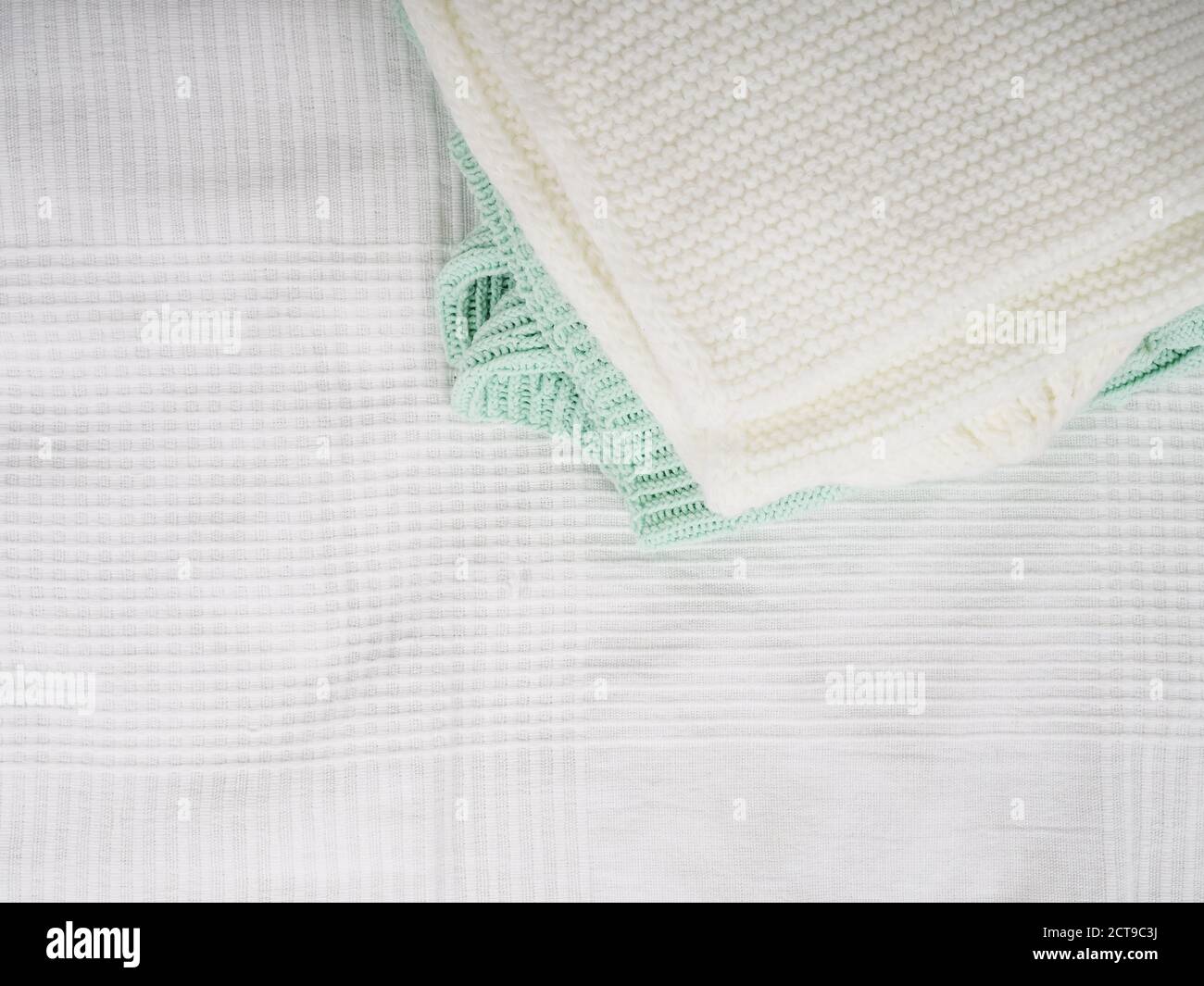Une pile de tricoté chauds sur un lit blanc. Vêtements confortables. Concept de ménage. Tricoté plié blanc Banque D'Images
