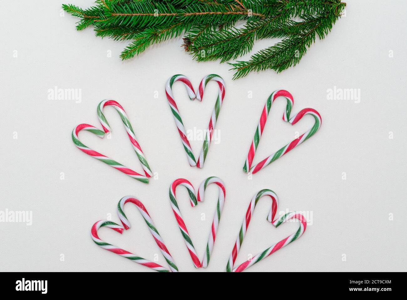 Vue de dessus. Forme de coeur en Cannes de bonbons et branche de sapin sur fond blanc. Banque D'Images