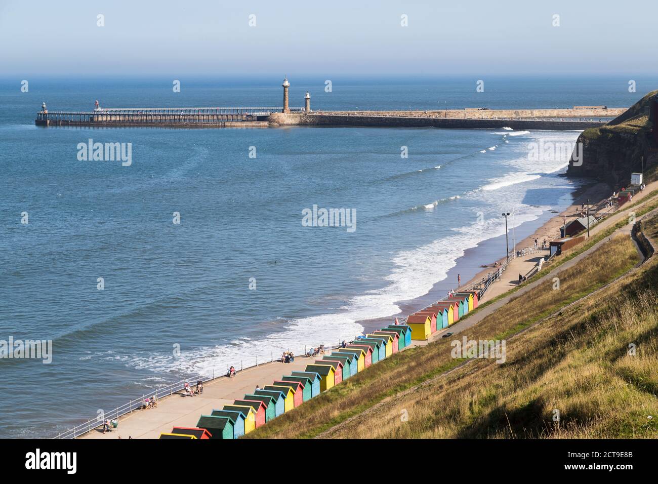 Chalets de plage le long de Whitby Sands menant à l'entrée du port de la ville de pêche. Banque D'Images