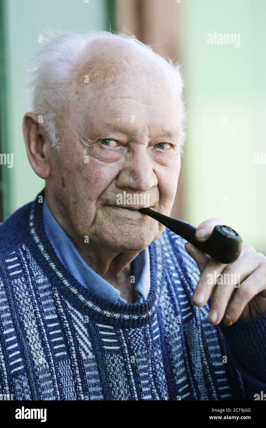 Allemagne, Portrait of senior man holding pipe, Close up Banque D'Images