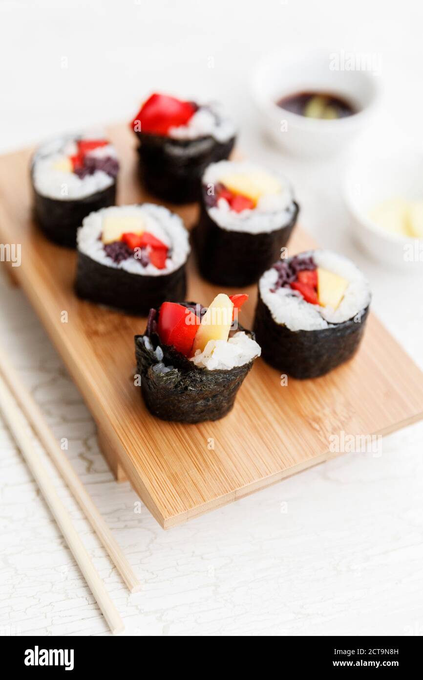 Futo Maki à la mangue et le poivron sur planche de bois, bols et baguettes Banque D'Images