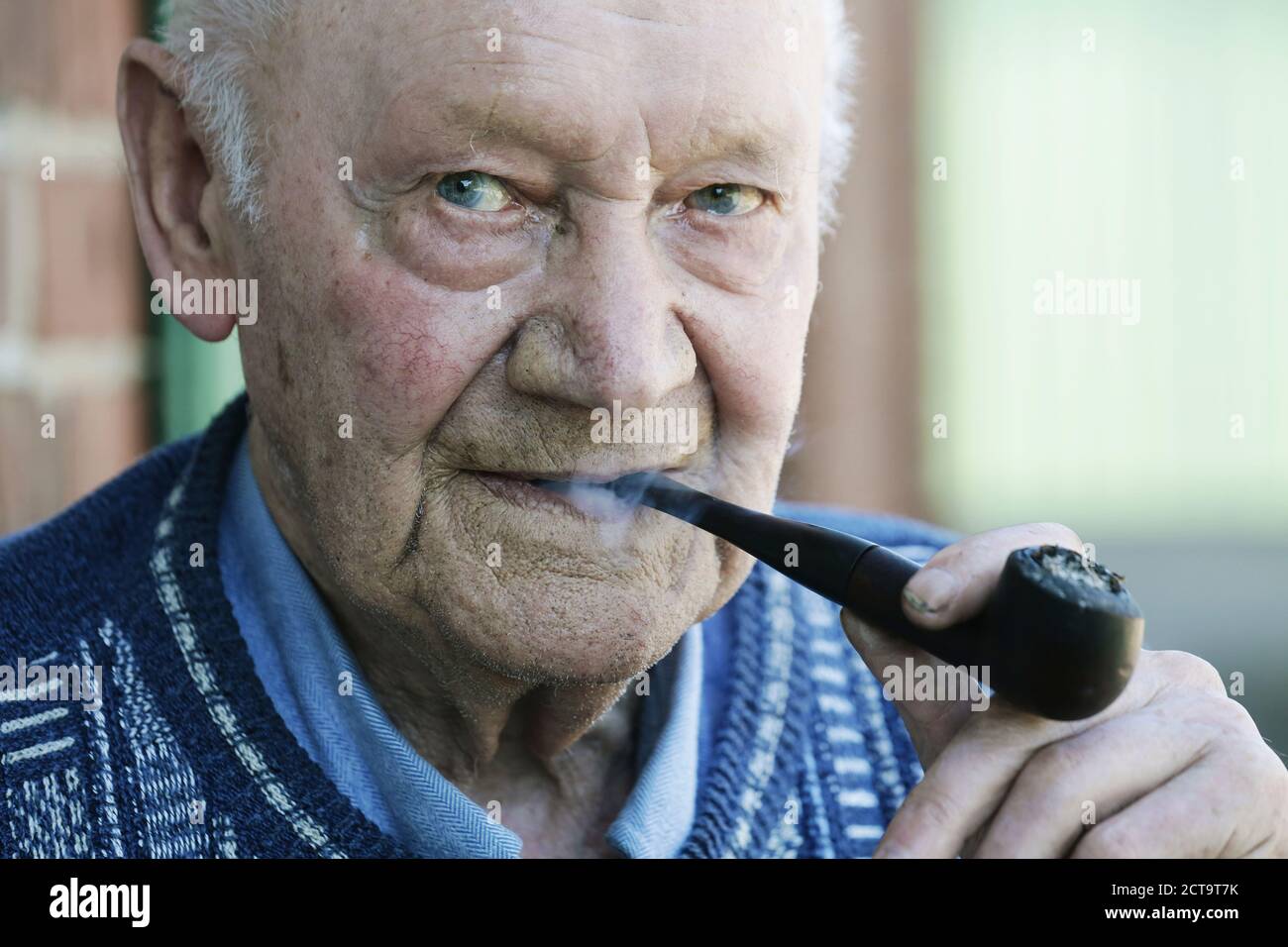 Allemagne, Portrait of senior man holding pipe, Close up Banque D'Images