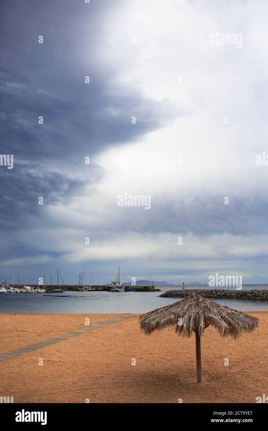 Portugal, Madère, Machico, jaune plage avec parasol, vue à Harbour Banque D'Images