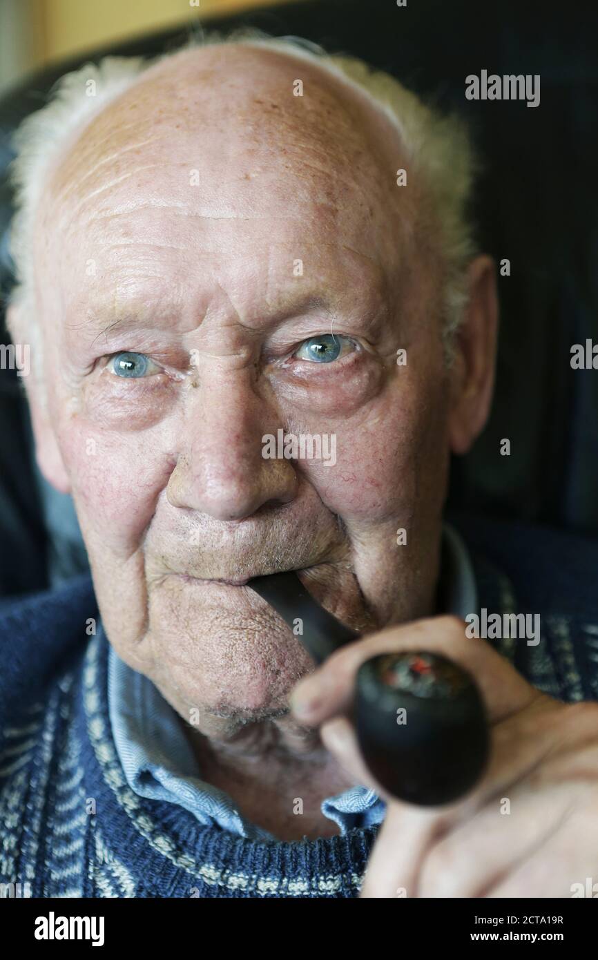 Allemagne, Portrait of senior man holding pipe, Close up Banque D'Images