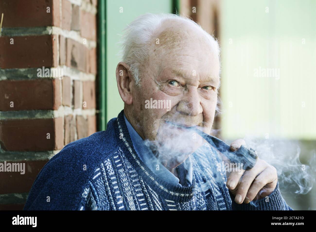 Allemagne, Portrait of senior man holding pipe, Close up Banque D'Images