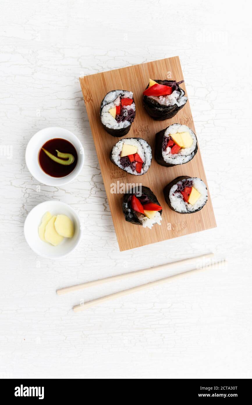 Futo Maki à la mangue et le poivron sur planche de bois, bols et baguettes Banque D'Images