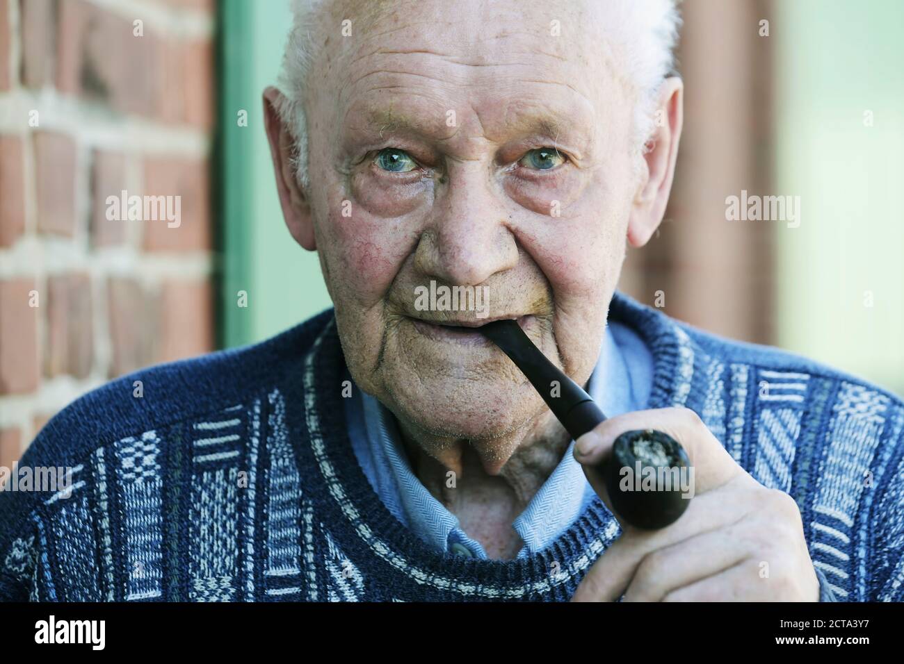 Allemagne, Portrait of senior man holding pipe, Close up Banque D'Images