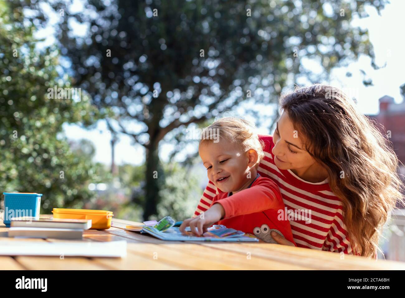 Happy Mother and Toddler Reading Lift-the-Rabat Childrens Book in the Jardin Banque D'Images