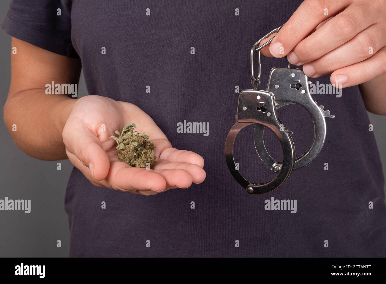 fille tenant en main un bourgeon de marijuana et menottes sur un fond sombre gros plan, drogue illégale. Banque D'Images