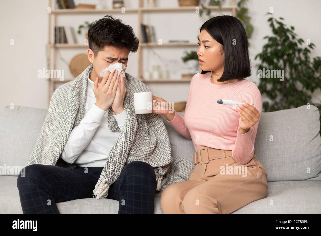 Femme asiatique traitant mari malade lui donnant la médecine à la maison Banque D'Images