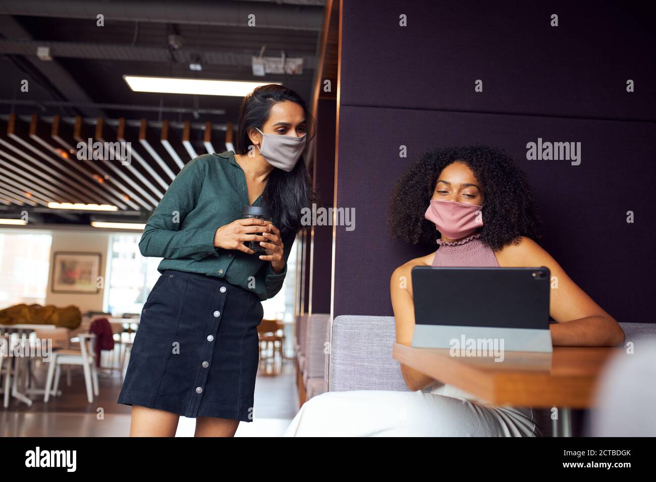 Femmes d'affaires portant des masques ayant eu des distances sociales à la réunion au bureau pendant Pandémie de santé Banque D'Images
