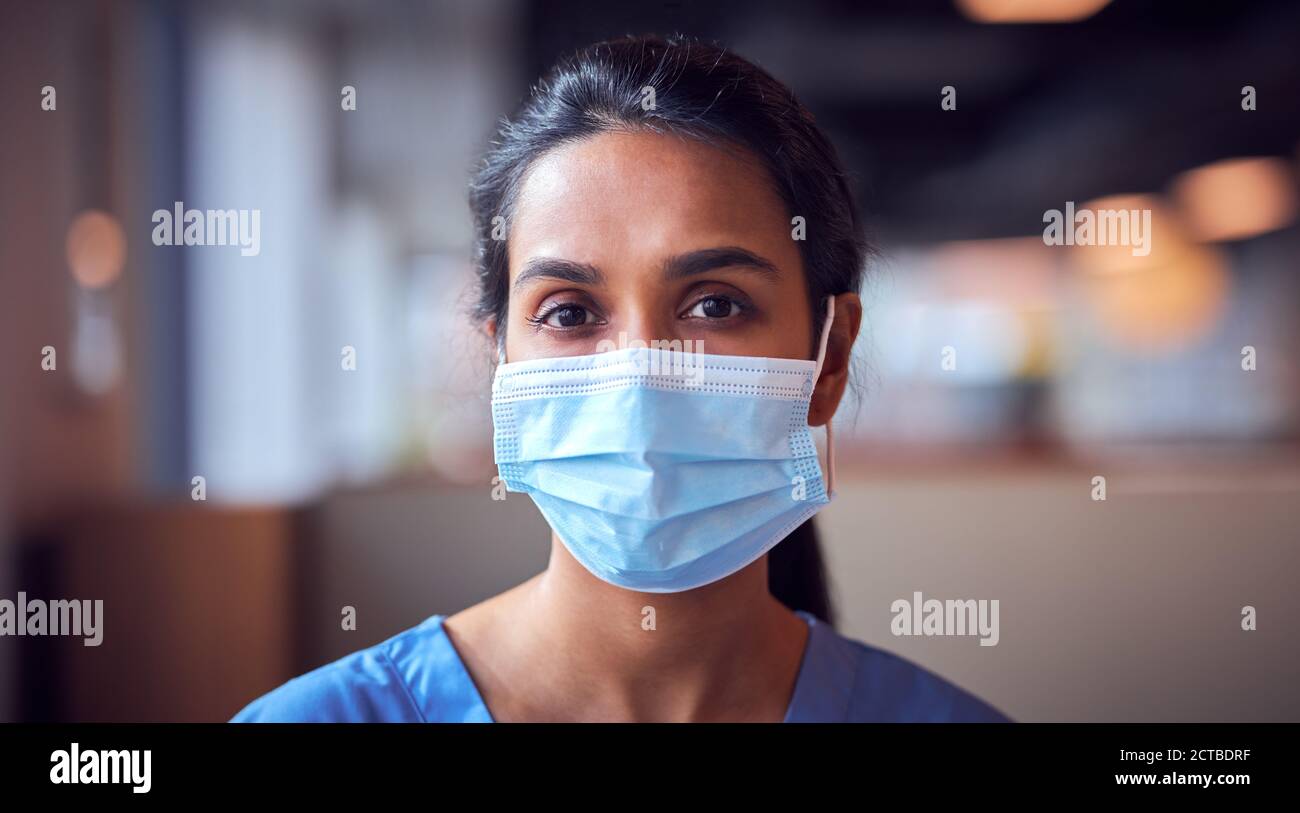 Femme Docteur en masque de visage portant des exfoliants sous pression dans Hôpital occupé pendant la pandémie de santé Banque D'Images