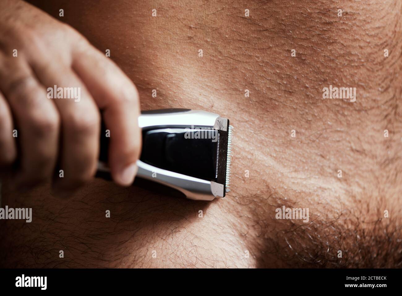 gros plan d'un jeune homme caucasien dans la salle de bains de tonte les cheveux de ses pubes avec une tondeuse électrique Banque D'Images