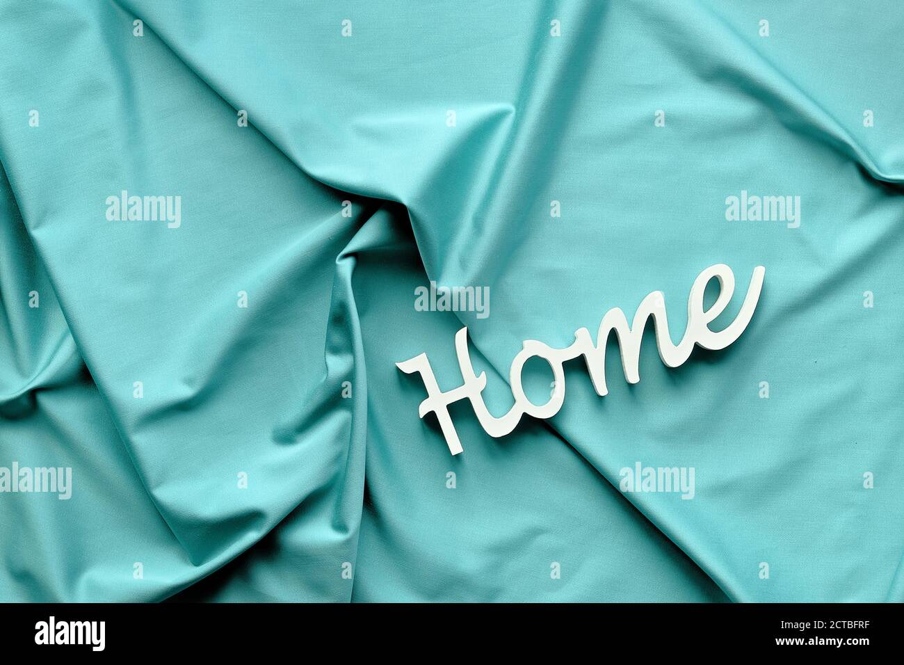 Ai Aqua - couleur tendance de l'année 2021. Vue de dessus très tendance, mot Home sur textile bleu menthe. Banque D'Images