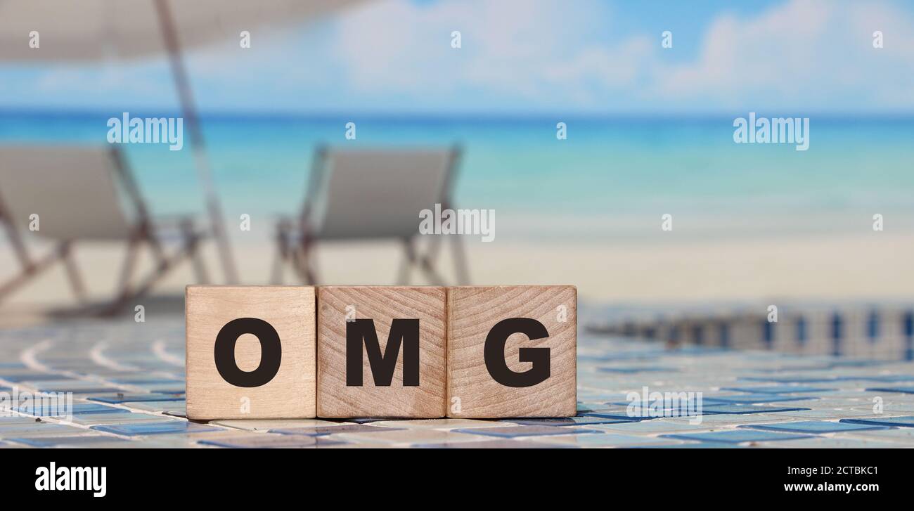 Le mot OMG des cubes en bois. Arrière-plan décontracté de la plage. Concept de style de vie Banque D'Images