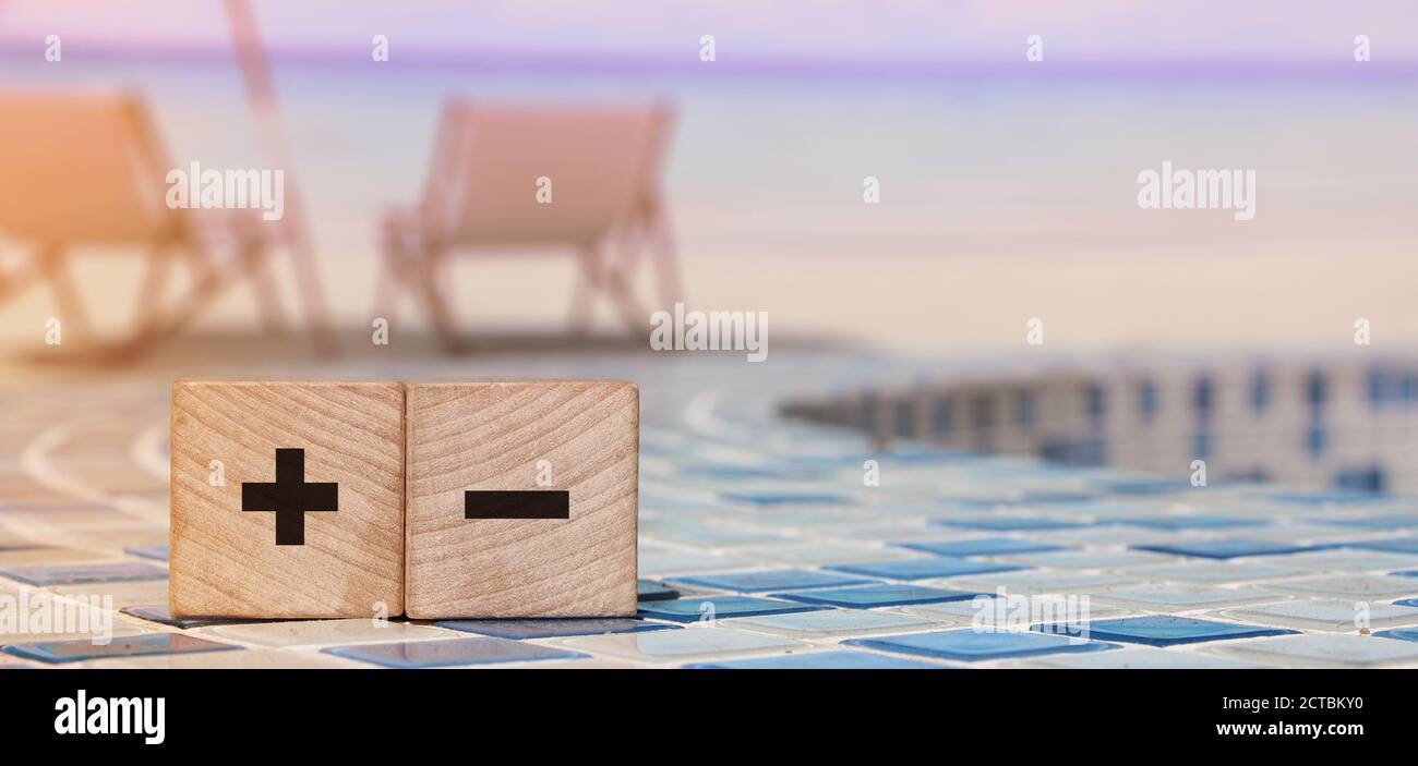 Signes plus et moins sur des cubes en bois sur un paysage de plage paisible. Business en ligne, achat en ligne alternatives concept d'évaluation Banque D'Images