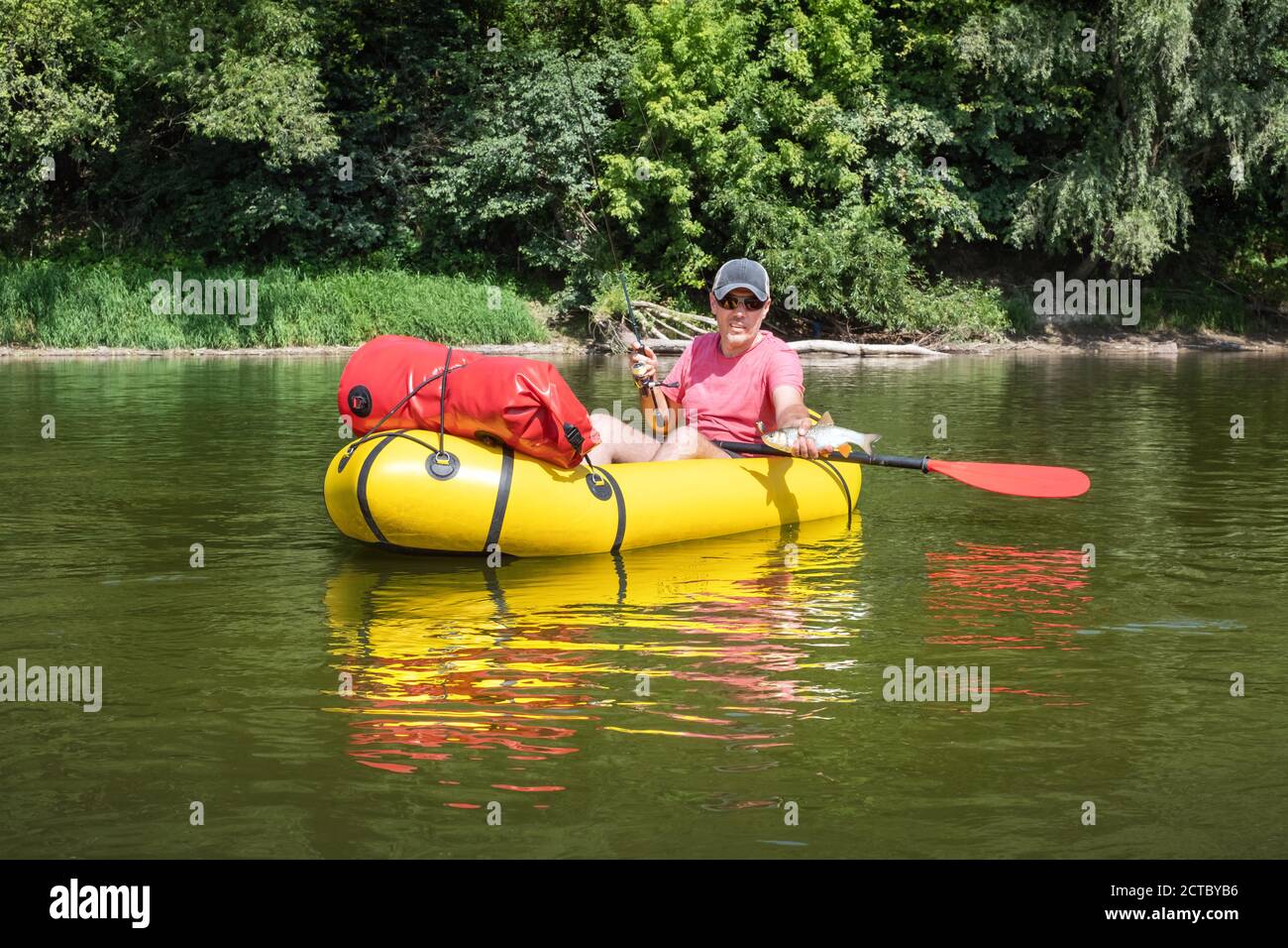 Homme mature pêchant à partir du bateau jaune sur le rivière en été Banque D'Images