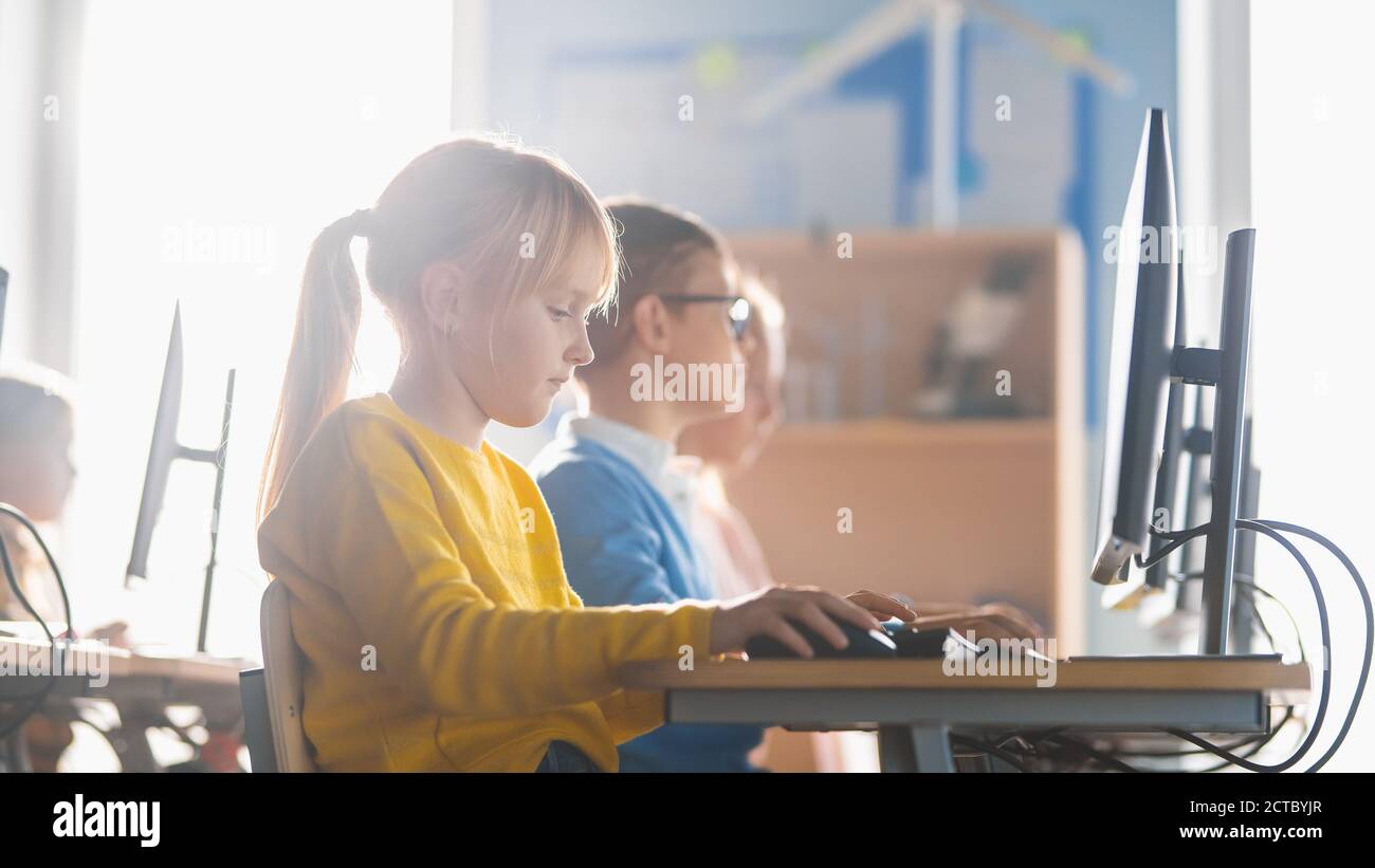 École élémentaire informatique en classe : Cute Little Girl utilise un ordinateur personnel, apprentissage du langage de programmation pour le codage de logiciels Banque D'Images